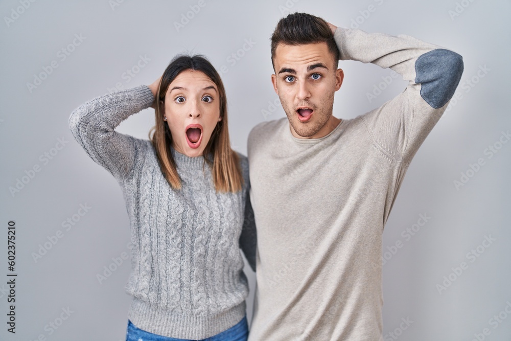 Young hispanic couple standing over white background crazy and scared with hands on head, afraid and surprised of shock with open mouth Young hispanic couple standing over white background crazy and scared with hands on head, afraid and surprised of shock with open mouth