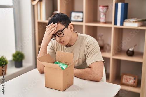 Photos Young arab man with open gift in cardboard box surprised with hand on head for mistake, remember error