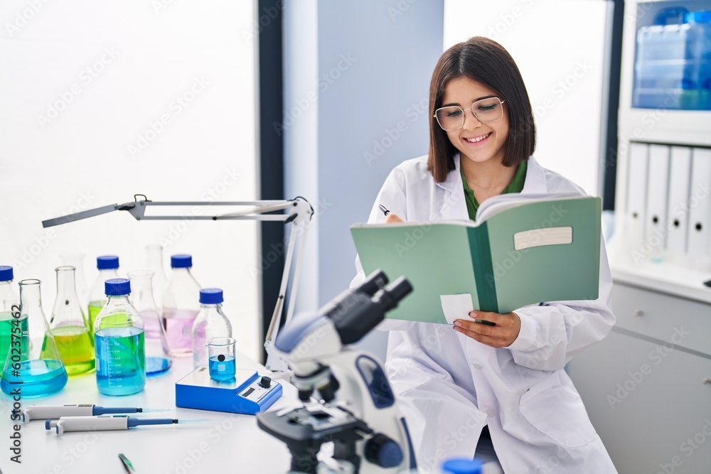 Young beautiful hispanic woman scientist smiling confident writing notebook at laboratory Young beautiful hispanic woman scientist smiling confident writing notebook at laboratory
