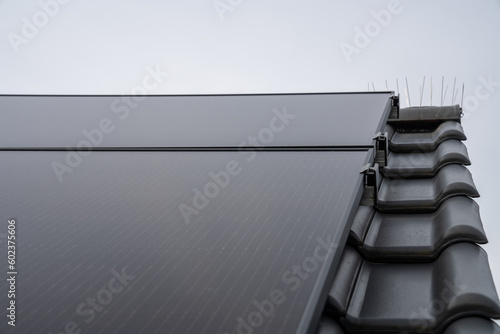 Diese PV-Anlage auf dem Dach einer modernen Wohnanlage nutzt die Kraft der Sonne, um erneuerbare Energie zu erzeugen. Die Solarpanels fangen das Sonnenlicht ein und wandeln es in saubere, grüne Energi photo