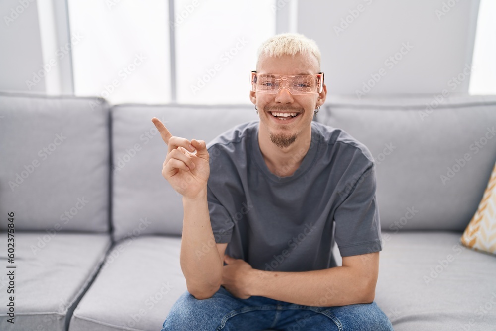 Young caucasian man wearing virtual reality glasses smiling happy pointing with hand and finger to the side Young caucasian man wearing virtual reality glasses smiling happy pointing with hand and finger to the side