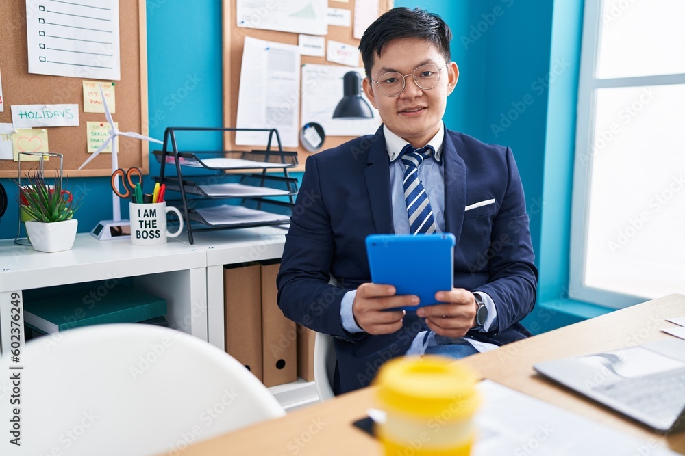 Young chinese man business worker using touchpad and laptop at office Young chinese man business worker using touchpad and laptop at office