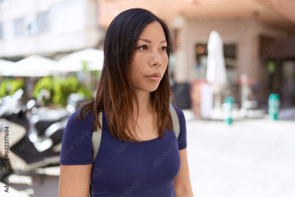 Young asian woman looking to the side with serious expression at coffee shop terrace Young asian woman looking to the side with serious expression at coffee shop terrace