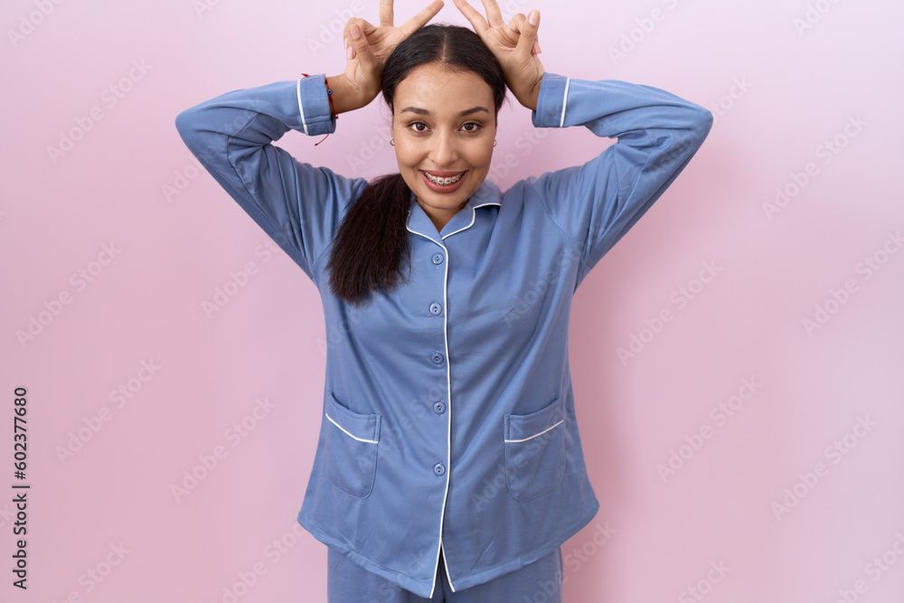 Young arab woman wearing blue pajama posing funny and crazy with fingers on head as bunny ears, smiling cheerful Young arab woman wearing blue pajama posing funny and crazy with fingers on head as bunny ears, smiling cheerful