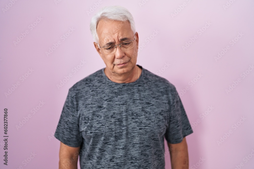 Middle age man with grey hair standing over pink background depressed and worry for distress, crying angry and afraid. sad expression. Middle age man with grey hair standing over pink background depressed and worry for distress, crying angry and afraid. sad expression.