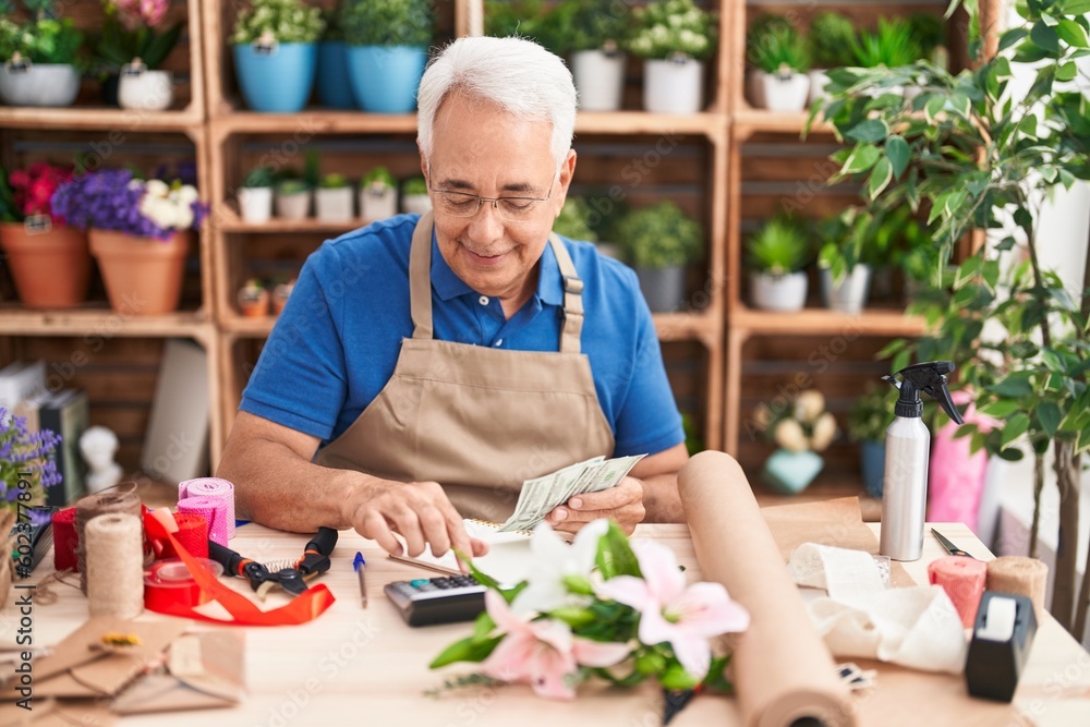 Middle age grey-haired man florist smiling confident counting dollars at florist Middle age grey-haired man florist smiling confident counting dollars at florist