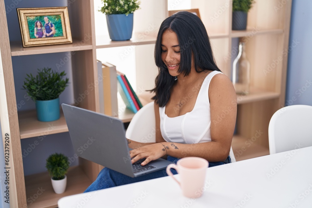 Young hispanic woman using laptop sitting on table at home Young hispanic woman using laptop sitting on table at home