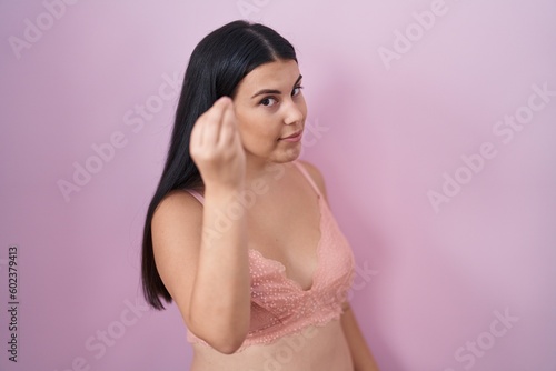 Young hispanic woman wearing pink bra doing italian gesture with hand and fingers confident expression