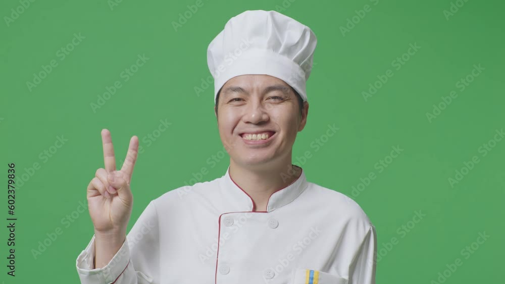 Close Up Of Asian Man Chef Smiling And Showing Peace Gesture To Camera While Standing In The Green Screen Background Studio
Close Up Of Asian Man Chef Smiling And Showing Peace Gesture To Camera While Standing In The Green Screen Background Studio