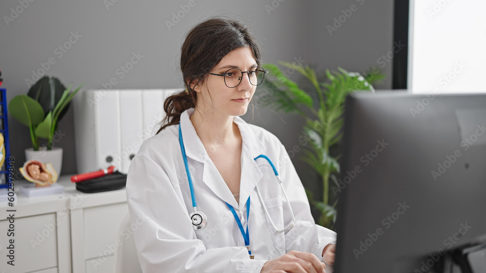 Young beautiful hispanic woman doctor using computer working at clinic