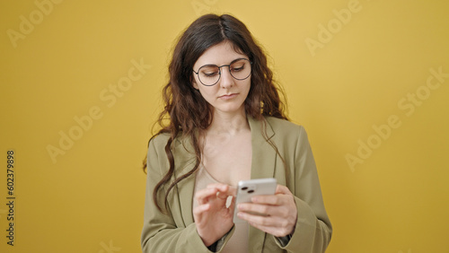 Young beautiful hispanic woman using smartphone over isolated yellow background
