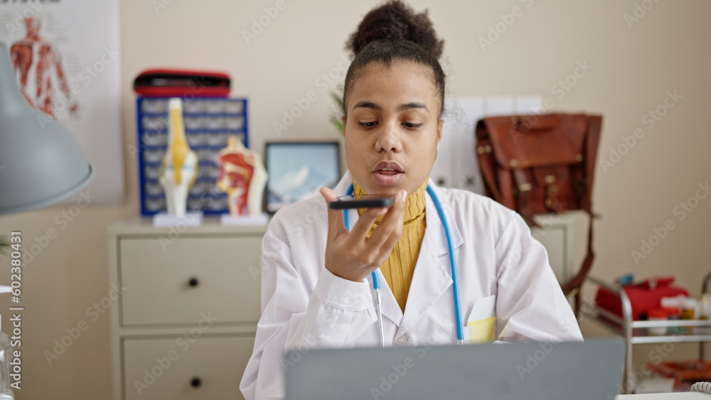 Young african american woman doctor sending voice message at clinic Young african american woman doctor sending voice message at clinic