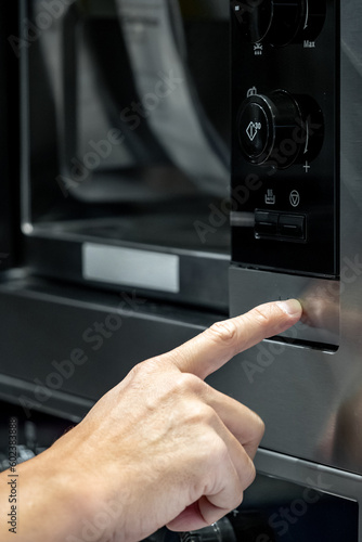 Male hand opening microwave door in the kitchen. Cooking appliance for domestic kitchen.
