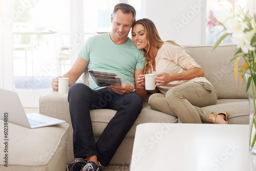 Reading, newspaper and mature couple on couch with tea, love and affection and relax together for holiday or news. Happy partner, woman or people on sofa with morning paper in lounge and coffee