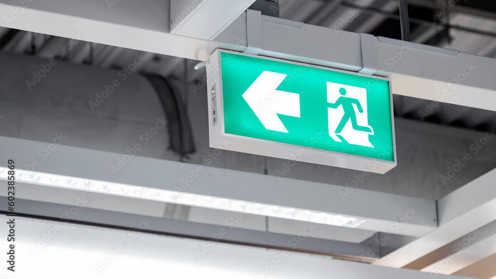 Emergency exit sign or fire exit sign hanging on ceiling structure in the building Emergency exit sign or fire exit sign hanging on ceiling structure in the building
