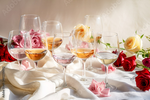 Romantic still life with different kind of wine in glasses on table with textile tablecloths with rosses on neutral grey background. Wine bar, winery, wine degustation concept. Generative ai