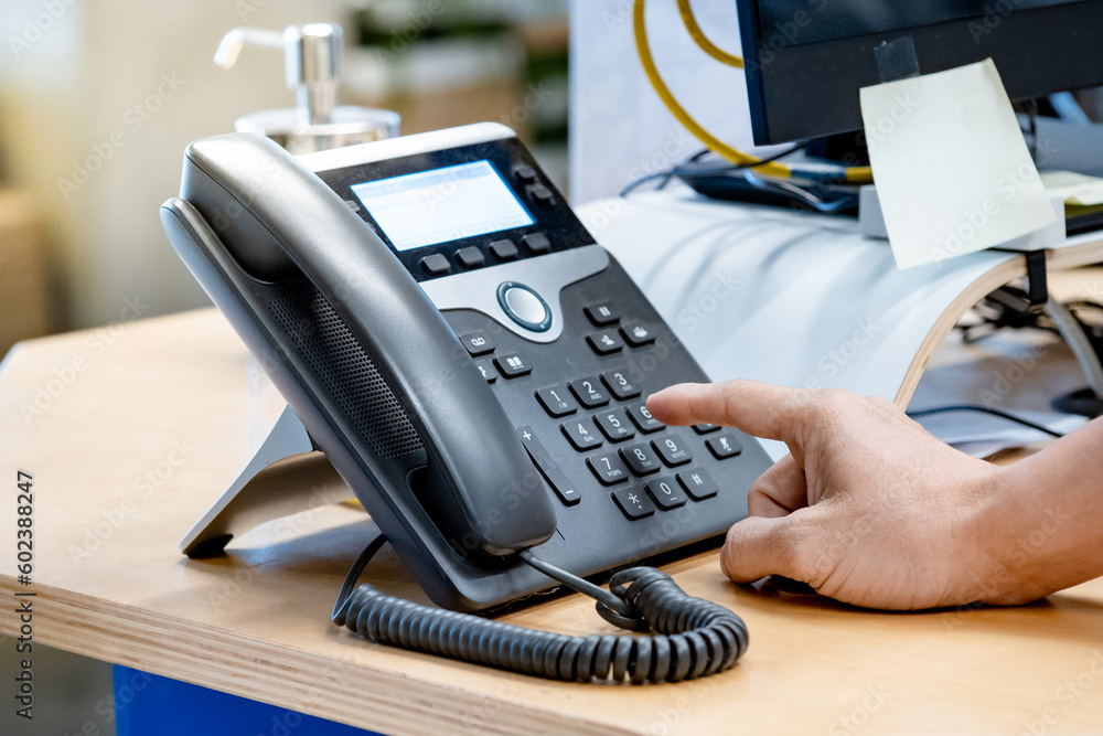 Call center and customer support. Operator hand trying to response customer call by using landline VoIP phone on help desk in the office. Call center and customer support. Operator hand trying to response customer call by using landline VoIP phone on help desk in the office.