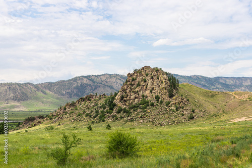 A huge rock with stone ledges. A smooth slope covered with rare plants. Omulevka Mountain, a natural monument.High cliff. photo