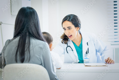 Pediatrician giving advice to mother of sick little girl at hospital.