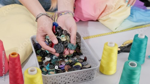 The girl acquires in both hands a lot of buttons from a plastic box. photo