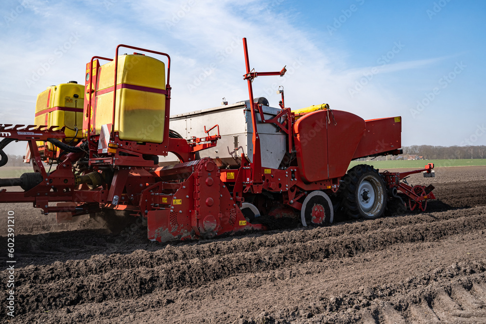 Kartoffelbestellung - Rote Kartoffellegemaschine beim legen von Saatkartoffeln - Seitenansicht Kartoffelbestellung - Rote Kartoffellegemaschine beim legen von Saatkartoffeln - Seitenansicht