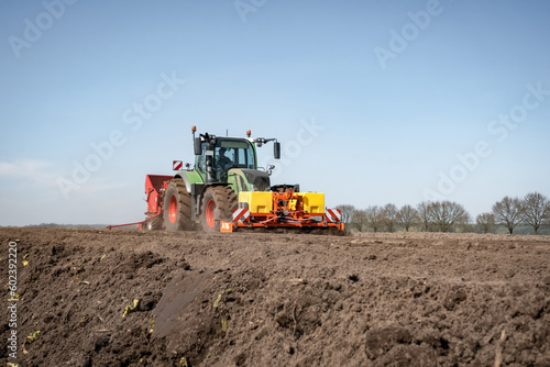 Moderne Landtechnik f  r die Bestellung des Katoffelackers im Einsatz -  Traktor mit Kartoffellegemaschine.