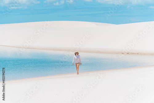 Wide shot of a woman in fresh rain water lagoon with white sand in a national park in the north east of Brazil.