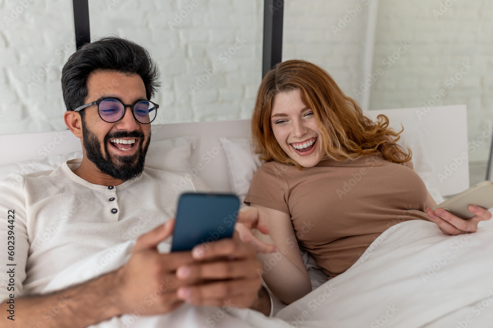 Man and woman spending weekend together in bed, using mobile phone, having fun, laughing. Man and woman spending weekend together in bed, using mobile phone, having fun, laughing.