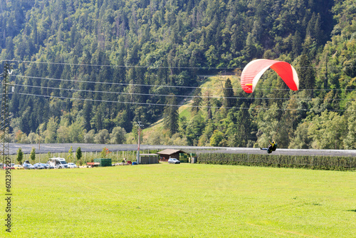 Tandem paragliders above apple plantation and mountain panorama near Saltaus, South Tyrol, Italy