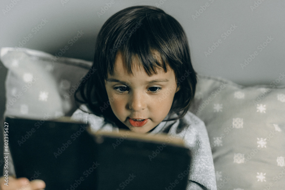 Little girl pray and read in bed with an Bible next to her Little girl pray and read in bed with an Bible next to her
