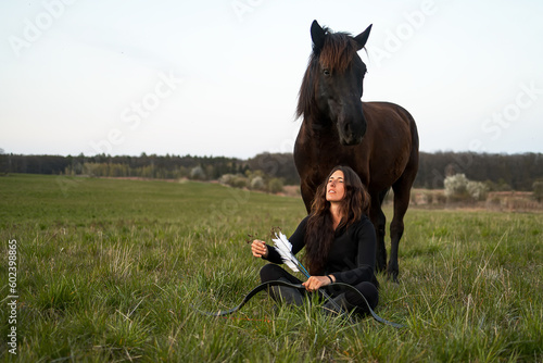 a young woman sitting under her horse and holding a bow