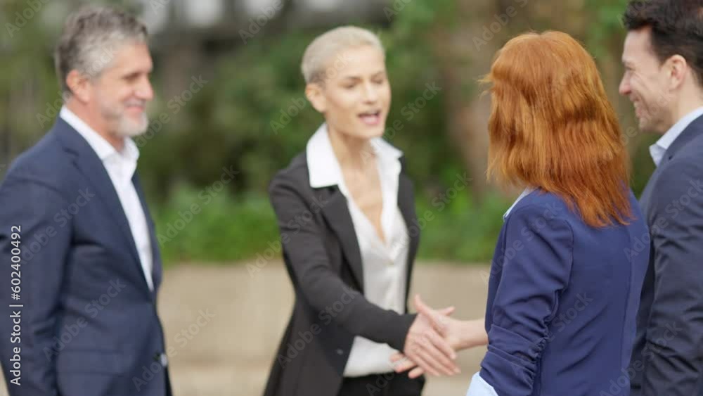 Businessman greeting a colleague shaking hands outdoors