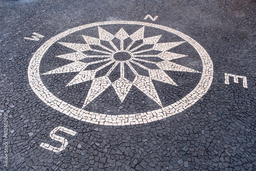 Compass lined with paving stones. Black and white mosaic floor from calcada tiling in Funchal, Madeira island, Portugal.
