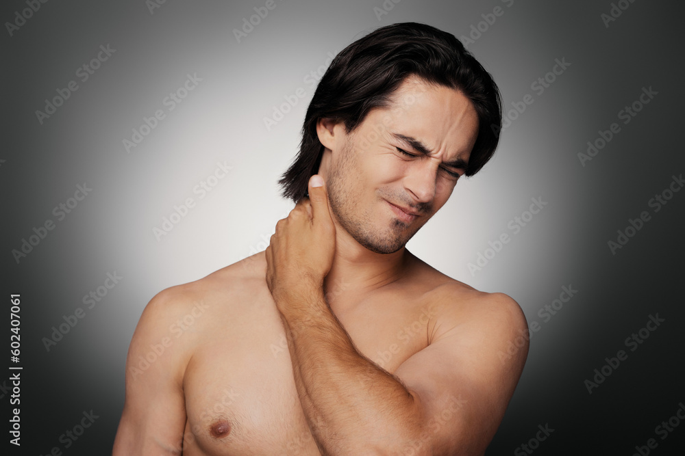 Portrait of frustrated young shirtless man touching neck against grey background Portrait of frustrated young shirtless man touching neck against grey background