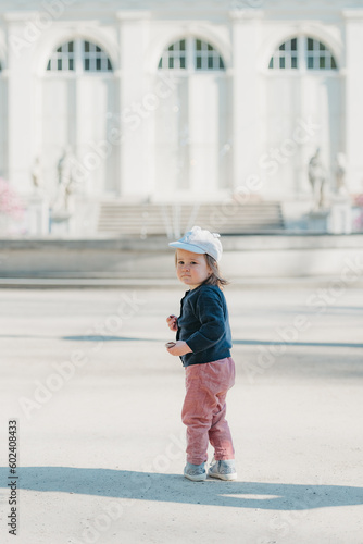 Obraz na płótnie A female toddler with her back in the yard of the European palace. w salonie