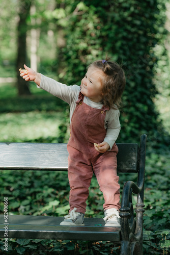 Obraz na płótnie A female toddler is on the garden bench in the park. w salonie
