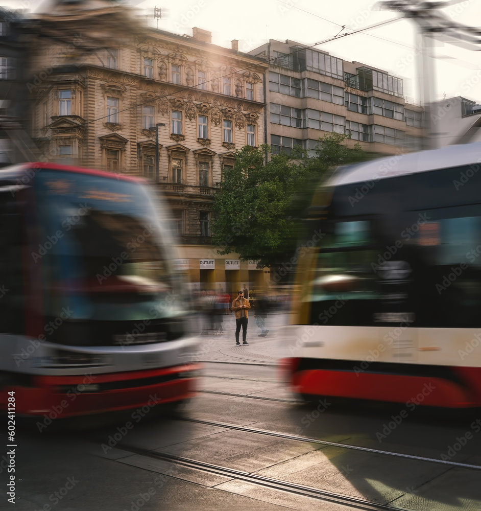 Prague, Czech - May 1, 2023: A man using cellphone in a busy environment with people walking around and tram in the foreground. hustle lifestyle concept. Long exposure shot.