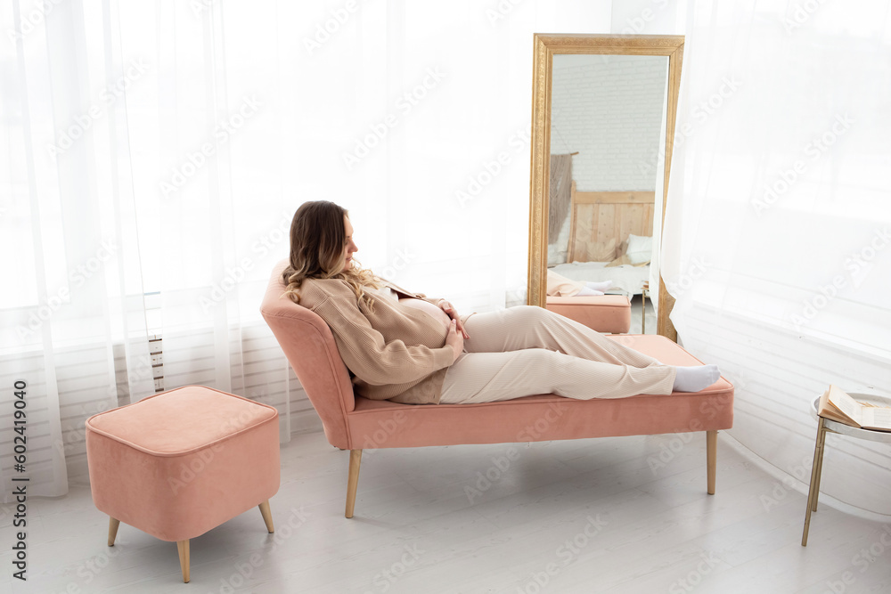 close-up of a pregnant woman on the bed hugging her pregnant belly. a beautiful pregnant woman lies on a sofa in a large beautiful living room near the window close-up of a pregnant woman on the bed hugging her pregnant belly. a beautiful pregnant woman lies on a sofa in a large beautiful living room near the window