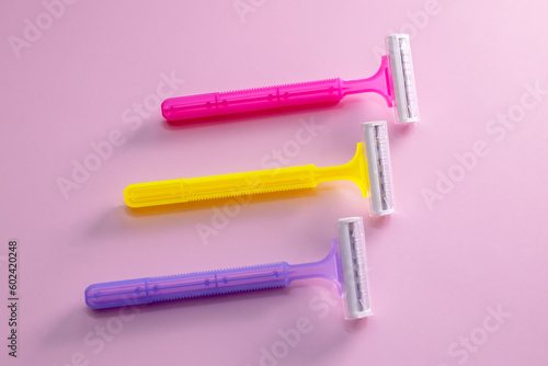 Different shaving razors for hair removal on pink background