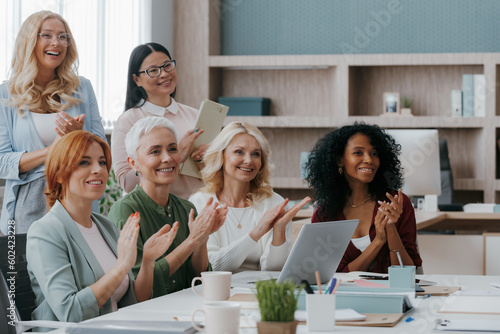 Group of mature women applauding while visiting business training class in the office © gstockstudio