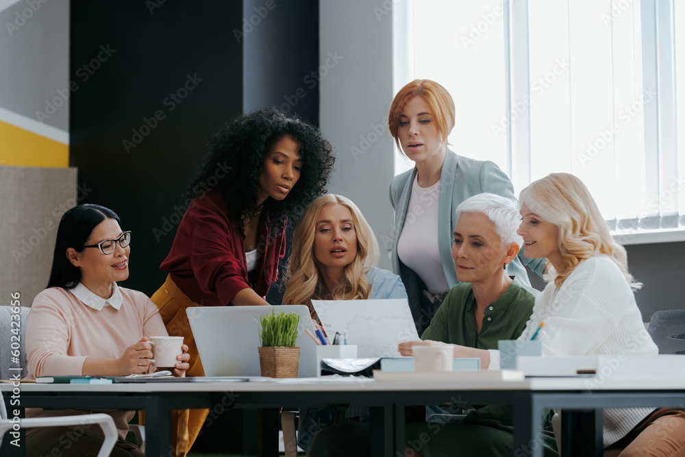 Group of confident mature women discussing business in the office together Group of confident mature women discussing business in the office together