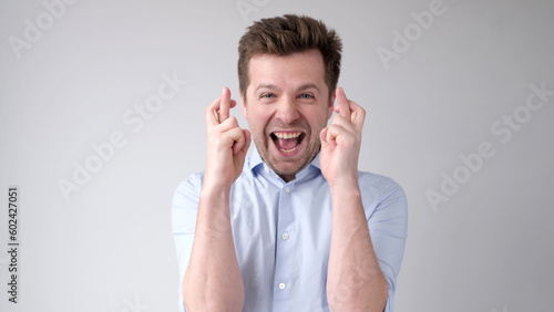 The European young man crosses his fingers, calling for luck