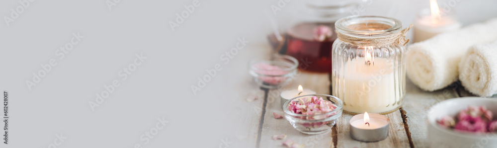 Aromatherapy. Organic natural floral, plant ingredients for spa treatment in salon. Rose petals, essential oil, burning candles, towels, delicious herbal tea, Atmosphere of relax, detention. Banner - obrazy, fototapety, plakaty 
