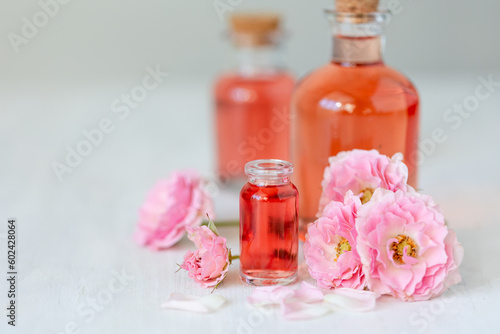 Concept of perfume with pure natural organic rose ingredient  essential oils. Glass bottles with flower herbal extract and elixir. Perfumery cosmetic toilet water fragrance  cream  skin care product