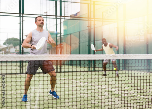 Portrait of man paddle tennis player during doubles couple match at court