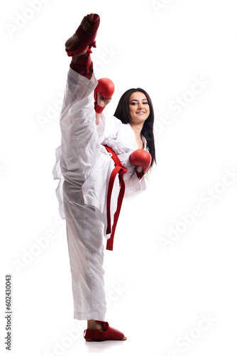 girl exercising karate leg kick wearing kimono and red gloves against white background