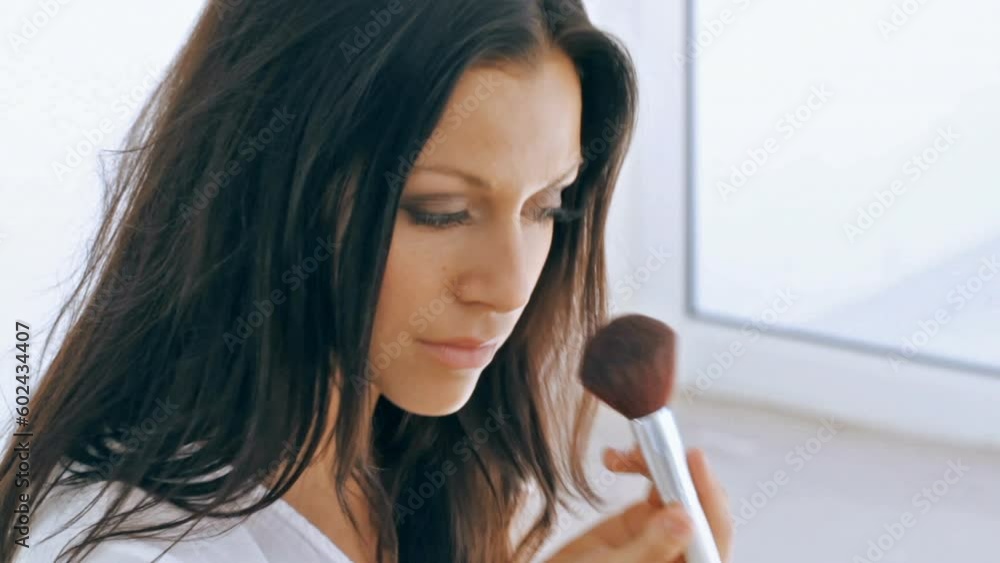 Woman applying makeup to her face in her lingerie and feeling confident. Gorgeous brunette wearing cosmetics for a radiant complexion. Flawless, bold and stunning eyes for everyday beauty looks.