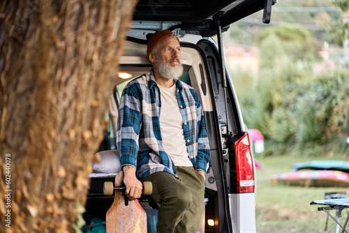 Canvas-taulu Active cool old hipster man standing near rv camper van holding skateboard
