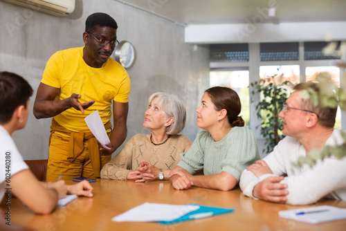 Experienced male coach conducts training for people of different nationalities