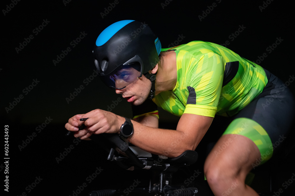 A triathlete rides his bike in the darkness of night, pushing himself to prepare for a marathon. The contrast between the darkness and the light of his bike creates a sense of drama and highlights the A triathlete rides his bike in the darkness of night, pushing himself to prepare for a marathon. The contrast between the darkness and the light of his bike creates a sense of drama and highlights the